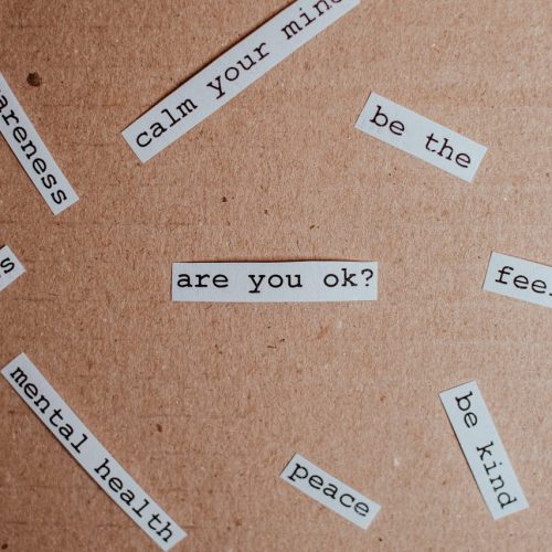 Cut-out words promoting mental health awareness on cardboard background.